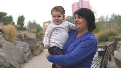 Obraz premium Happy smiling grandmother and little cute granddaughter at park