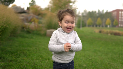 Portrait of cute little girl laughing with funny look outdoors