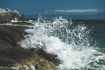 Splash of sea water waves hitting the rocky beach
