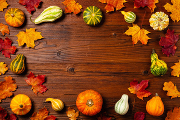 Wooden background. Arranged autumn leaves and pumpkins. Top view.