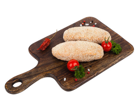 Raw poultry chop devolay with butter. Shown on a brown chopping board. Breaded in a bun. Pack shot. White background.
