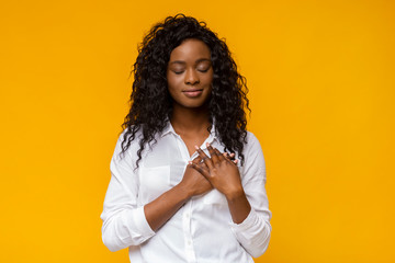 Appreciative afro woman placing hands on her heart