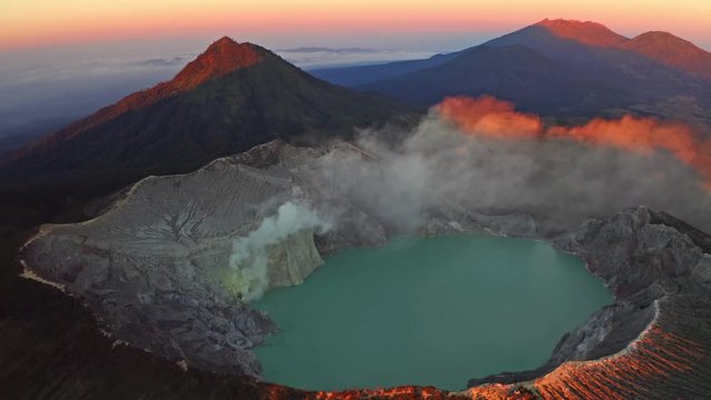 Aerial view of rock cliff at Kawah Ijen volcano with turquoise sulfur water lake at sunrise. Panoramic view at East Java, Indonesia. Natural landscape background.