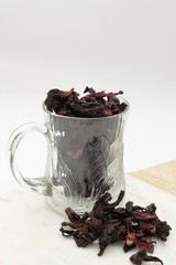 Raw dried hibiscus flower with glass cup.