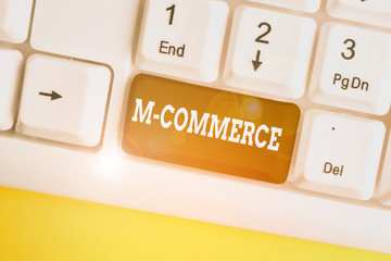 Conceptual hand writing showing M Commerce. Concept meaning commercial transactions conducted electronically by mobile phone White pc keyboard with note paper above the white background