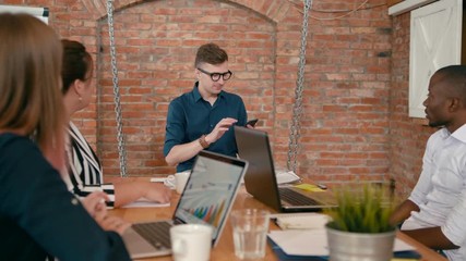 Business Man Team Leader or Trainer is Discussing Project to Employees in Startup Loft Office. Teamwork or Seminar in Diverse Group of People. Meeting at Work. 4K Gimbal Panning Shot in Slow Motion