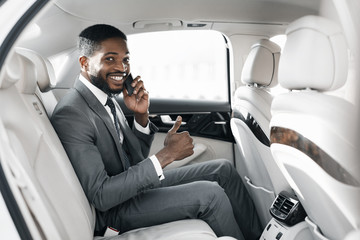 Young afro businessman in luxury car, showing thumb up