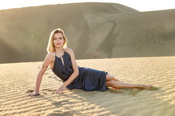Fototapeta na wymiar Portrait of blue eyed girl in blue dress in desert