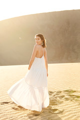 Fototapeta na wymiar Glamorous brunette in white dress in desert, portrait