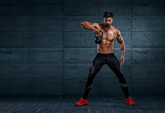 Handsome Bodybuilder Exercising With Kettlebell. Copy Space for text