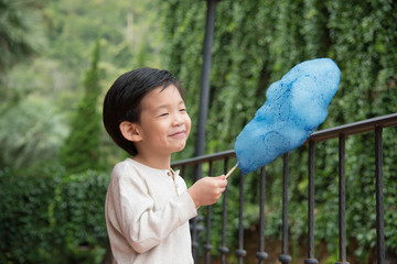 Cute Asian child eating blue cotton candy in the park