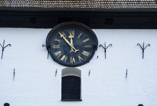 church clock on a white wall on an old tower. View from below.