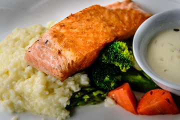 pan fried salmon chunk served with creamy rice risotto and boiled vegetables
