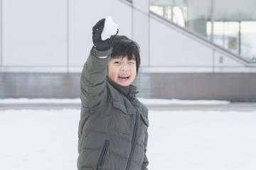 Cute Asian child playing on snow in the park