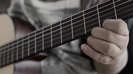 Close-up hands of man playing acoustic classical guitar with dark and grain processed