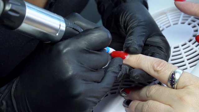 Close up. Electric Nail Drill in Manicure Salon. Hardware manicure in a beauty salon. Female manicurist remove old gel from clients nails.  Suction grill. Nail manicure process in a beauty salon.
