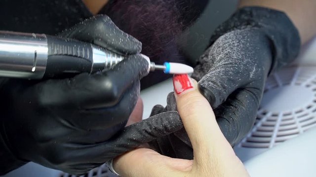 Close up. Electric Nail Drill in Manicure Salon. Hardware manicure in a beauty salon. Female manicurist remove old gel from clients nails.  Suction grill. Nail manicure process in a beauty salon.