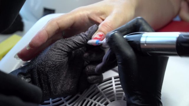 Close up. Electric Nail Drill in Manicure Salon. Hardware manicure in a beauty salon. Female manicurist remove old gel from clients nails.  Suction grill. Nail manicure process in a beauty salon.