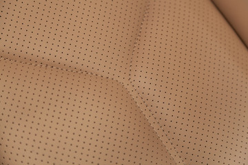 Part of leather car headrest seat details. Сlose-up beige  perforated leather car seat. Skin texture
