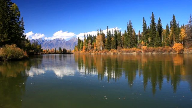 Siberian autumn beautiful landscape with the Eastern Sayan Mountains. Yellowed trees are reflected in the Irkut River. Baikal region, Buryatia
