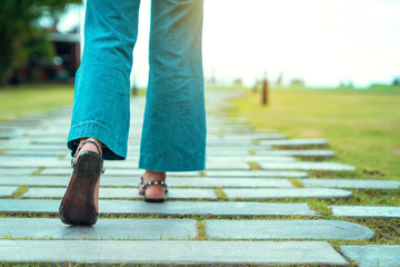 jeans walking wearing Sandals on the stone walkway with grass ground
