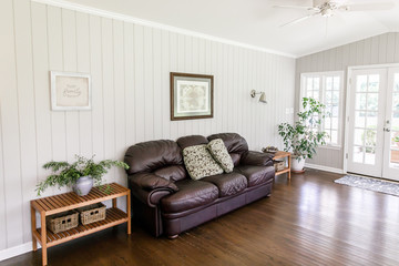 Plush and soft leather couch in a bright and airy sun room living room den in a 1950's house
