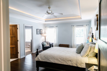 Master bedroom with king size bed and tray ceilings with uplighting and hradwood floors