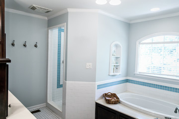 bathtub area of 1950's style bathroom with tile floor and dark brown cabinets in white and blue...