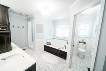 1950's style bathroom with tile floor and dark brown cabinets in white and blue accents wit a...