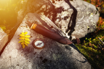 Bushcraft equipments on a rock. Compass and knife in forest. Hiking and survival concept.