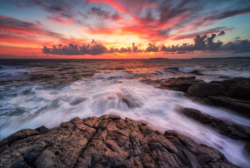 Obraz premium Stormy sea with colorful sunrise sky at the rocky coastline of the Black Sea
