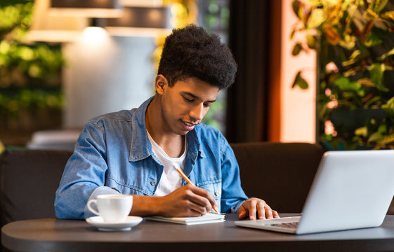 Young male blogger making notes for publication ides at cafe