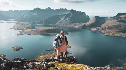 A couple of young people in love stand hugging on top of the Voladstinden mountain in Lofoten islands in Norway.