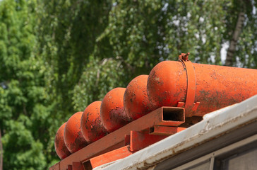A set of refillable cylinders on a vehicle roof containing natural gas used as fuel, over background of green trees. Concept of environmentally friendly energy source.