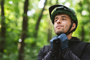 Young man wearing his sport helmet on forest background