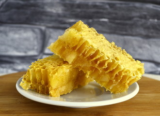 Honeycombs with honey and pollen on a white plate.