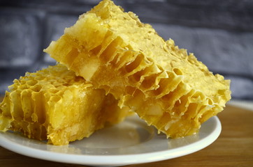 Honeycombs with honey and pollen on a white plate.