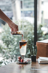 man pouring coffee into cup of coffee in cafe