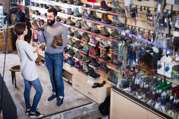 Positive couple examining various shoes in sports store