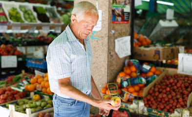 Elderly man looking for fruits in market