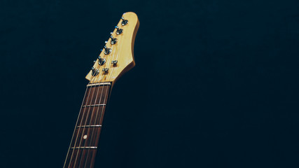 Professional music class. Electric guitar headstock over dark background. Copy space.