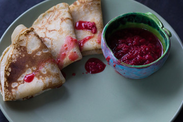 Blini triangles or crepes on plate with raspberry jam