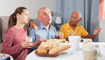 Family of three emotionally watching sports on tv while drinking beer at home