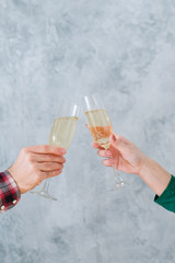 Romantic date. Cropped shot of couple clanging champagne glasses over blur textured gray wall background. Copy space.