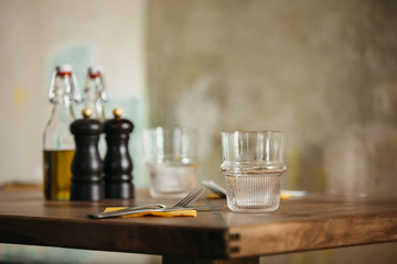 Closeup of a water glass on a wooden table in a rustic italian restaurant