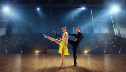 Fototapeta na wymiar Couple dancers perform latin dance on large professional stage. Ballroom dancing.