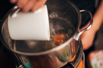Chef pouring egg in a boiling water