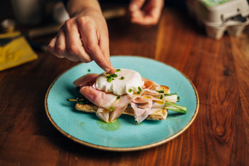 Female chef plating Eggs Benedict