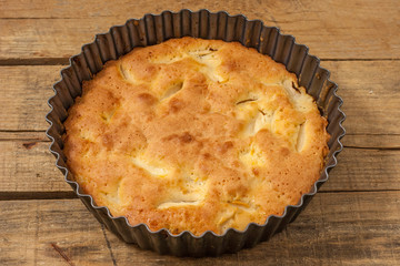 Apple Pie Charlotte on a wooden table in iron form, top view