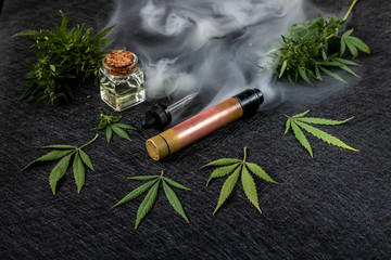 Cannabis liquid. Vape CBD or THC, Vaping Marijuana Leaves and Hemp. On a dark background. Mist of...